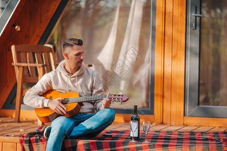 烧烤吉他成人在秋天坐他家阳台上的年轻人秋天坐在阳台上的快乐男人图片