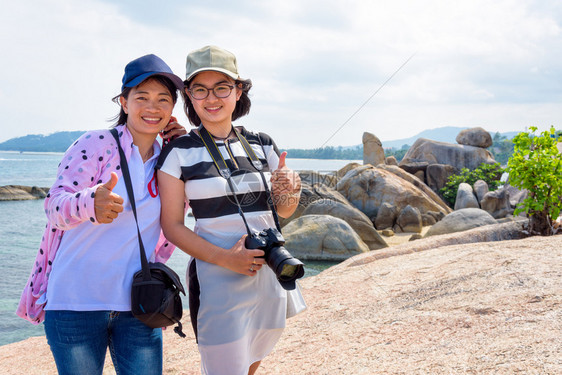 女士热带母亲和儿站起大拇指在欣达爱蓝色海的美丽自然景观和天空中笑暑假旅行时泰国母亲和女儿在兴田欣泰的观点下在苏拉特萨尼KohSa图片