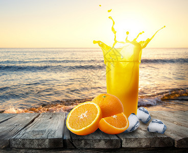 茶点橙汁杯子在木制桌上喷洒橘和冰一杯果汁站在海日落前的桌子上休息和度假的概念橙汁杯子和冰在木制板上喷洒新鲜图片