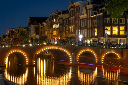 城市照明荷兰在阿姆斯特丹的夜晚运河不光化桥和船尾在滨水边夜间运河桥和阿姆斯特丹大厦上的荷兰传统住房b荷兰传统住房建筑物图片