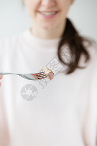 盘子饮食新鲜的女孩手里拿着一块金鱼放在叉子上亚洲食物特写垂直照片女孩手里拿着一块金鱼放在叉子上亚洲食物特写垂直照片图片