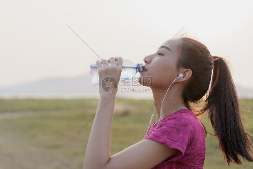 人们年轻的松弛亚洲健身运动员女侧面观点她们喝着瓶装水在锻炼后或夏季日出时奔跑后放松概念健康与生活方式图片