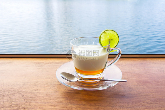 潘皮萨尔含海水表面背景的棕色木制桌面上的清玻璃杯中柠檬酸奶鲜白色的碗图片