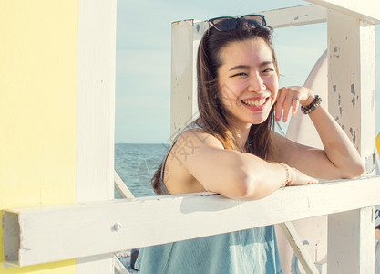 潮人游客靠近坐在海滩附的亚洲美丽女士带着快乐的笑容微着旅行和夏天的概念图片