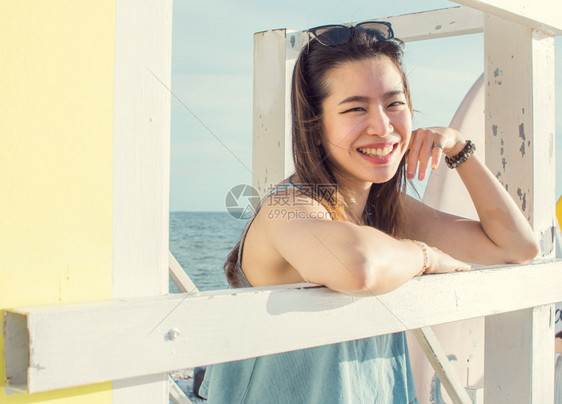 潮人游客靠近坐在海滩附的亚洲美丽女士带着快乐的笑容微着旅行和夏天的概念图片