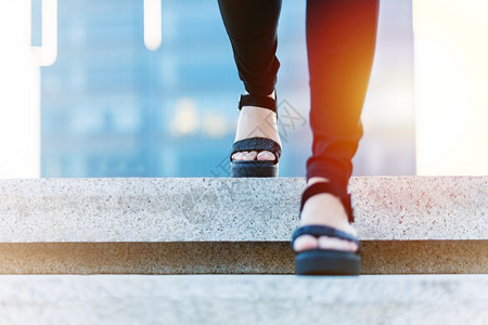腿妇女走向成功商人青年妇在楼梯上向前迈步进女企业家正在走上楼梯积极的上图片