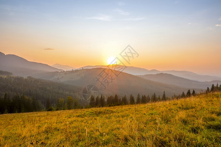 绿色太阳落下在一个无云的天空中在山顶之上太阳在夏日山上升起天空没有乌云日落户外图片