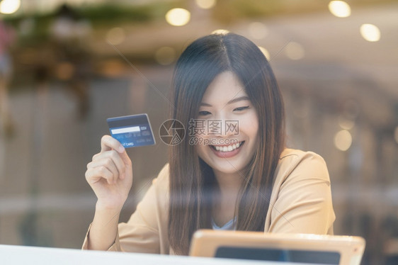 扫描亚洲妇女利用信卡和移动电话在百货商店通过服装背景技术钱财包和网上支付概念信用卡模型在线购物亚洲妇女使用信卡和移动电话在服装店图片