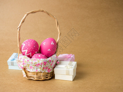复活节时在左边角落的棕色背景复活节彩蛋含棕色背景鸡蛋和彩上涂的褐色复活节蛋中一个篮子编织木和礼物盒中的复活节鸡蛋纸阴影红色的图片