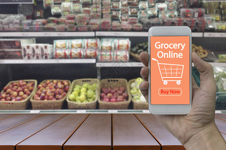食物商品手持智能机在杂货店内部背景的模糊超级市和零售商店上屏幕使用网杂货店交图片