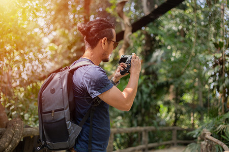 冒险相机年轻的亚洲男子背包和旅行者一起走在欢乐地森林上拍照假期概念旅行时间较慢图片