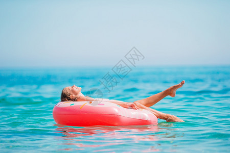 海中小女孩躺在泳圈里享受太阳游泳图片