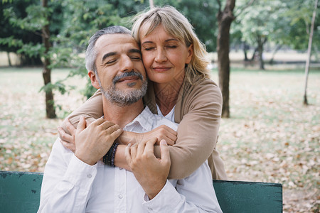 女快乐的老人夫妇坐在长椅上早花园抱一起表情相爱的老夫妇拥抱图片