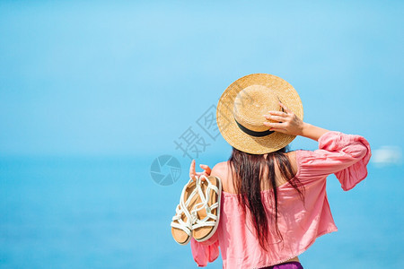 乐趣年轻女士在海滩度假时的背影年轻快乐的女士在海滩上有山风景水鞋图片