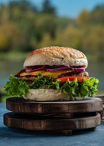 芝士汉堡烧烤果汁美味的奶酪汉堡配有牛肉生菜泡番茄和洋葱圈放在木制餐桌上的经典街头食品烤汉堡芝麻图片