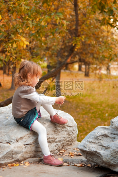 秋天随意的颜色3年小女孩在秋季公园晚上绑鞋带和图片