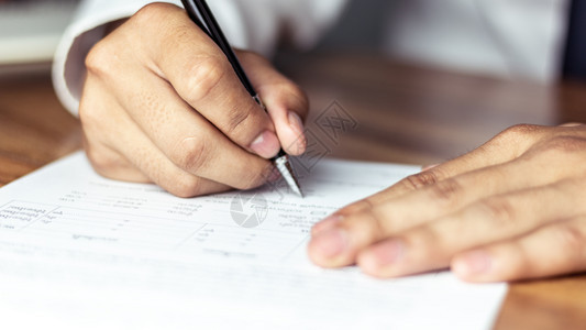 信商人在一份办公文件上签字形式合同图片
