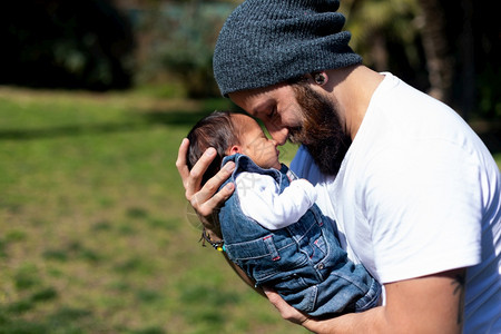 快乐的年轻父亲拥抱和吻他可爱的新生婴儿保持脸童年图片