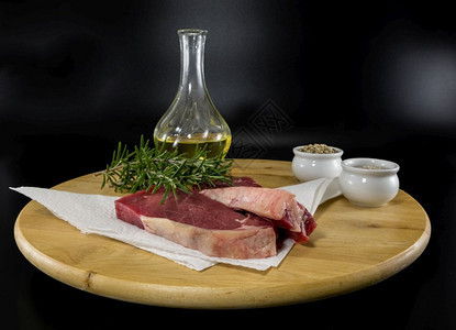 木制餐盘上两份菜牛排配有橄榄油迷迭香盐和辣椒准备烘烤烧市场肉图片