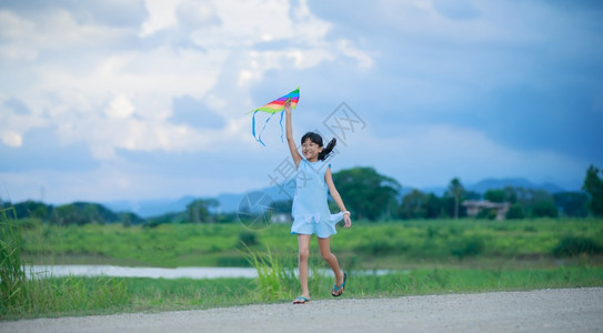 自然天空亚洲女孩带着风筝跑来去夏天在草地上欢乐的亚裔女孩喜悦图片