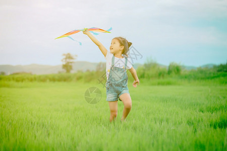 亚洲女孩带着风筝跑来去夏天在草地上欢乐的亚裔女孩年轻一种幸福图片