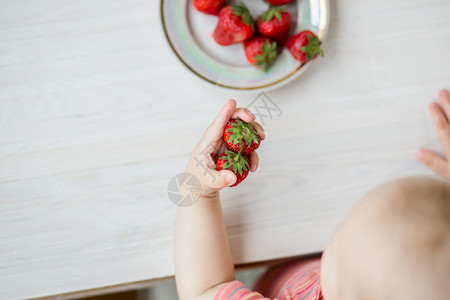 诱惑乡村背景中带草莓的孩子手一盘草莓夏季健康饮食的概念从上面看公寓乡村背景中带草莓的孩子手一盘草莓杯子图片