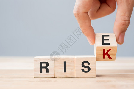桌子商人用手翻木板块将RISK改为经济机会态度和危概念表背景经济机会和危概念上的RISE案文增加战略图片