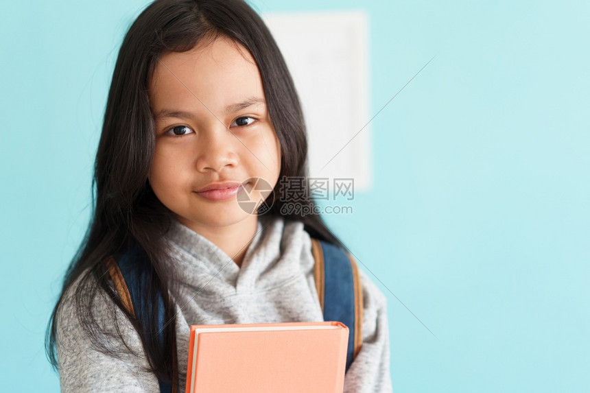 年轻的尽管亚洲儿童拿着书本和背包站在家庭内部的肖像中一个孩子看着摄影机学校时的背包CicleCivitykacktoschool图片