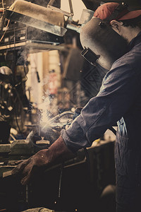 氩气保护的焊工正在用防护面罩焊接车库中的金属零件工业钢焊作机正在用防护面罩焊接车库中的金属零件工业钢焊机人图片
