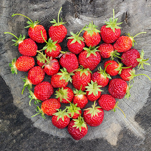覆盖收成草莓红心形状在老碎裂的树桩上女主人爱草莓夏天贺卡草莓红心形状在老碎裂的树桩上水果图片