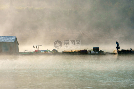 在大雾的清晨房子在湖面上的大雾中蒸气从水流到空中男人走在回家的路上美丽高原风景越南薄雾目地图片