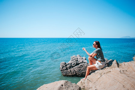 女士在悬崖海岸边缘的露天快乐妇女享受在山顶岩头的景色在悬崖海岸边缘的露天旅游女客美丽的图片