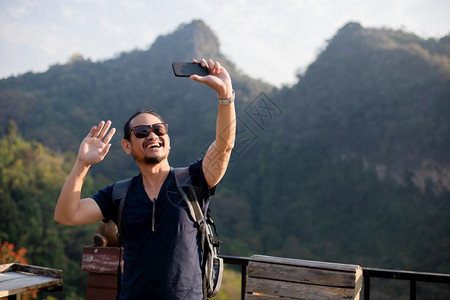 乐趣亚洲男旅游者正在使用手机自拍通过社交网络在媒体上分享校对Soup联网电话图片
