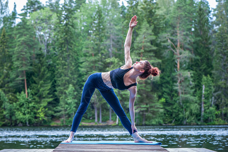 身体灵活Yogi女孩练习瑜伽做UtthitaTrikonasana运动延伸三角形在湖上摆姿势放松图片