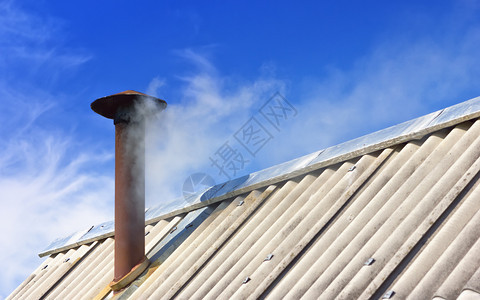 可选择的蓝天对着烟囱废白云层抽象概念背景有复制空间选择地聚焦于影印空间在一块旧房子白色烟雾覆盖的屋顶板上拉斯蒂烟管道建造图片