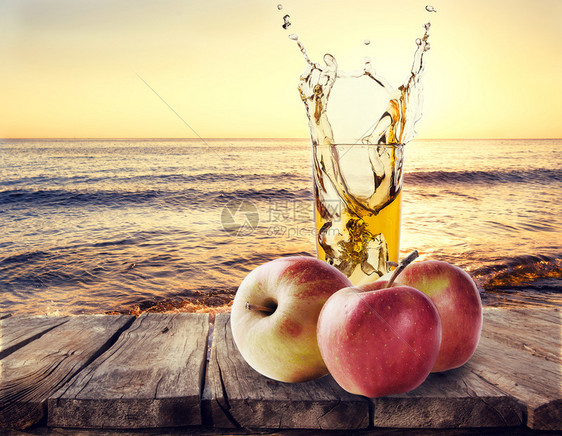 苹果汁和杯子木板上的苹果放在木桌上以海景背为苹果汁与杯放在木桌上喝甜的门户14图片