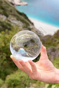 蓝色的手握水晶球靠近海滨和山顶春天高度图片