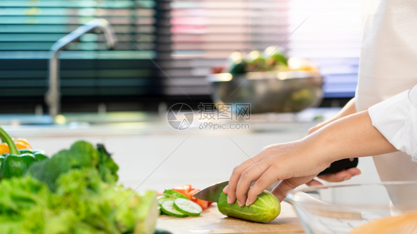 切割亚洲年轻妇女正在通过切黄瓜制作健康食品蔬菜沙拉用于在轻食厨房家烹饪和健康食品概念的切餐板上配菜成份厨师红色的图片