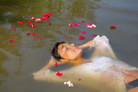 池塘夏天哥伦比亚妇女乘着玫瑰花瓣漂浮在自然水中幸福图片