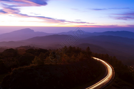 黎明时的美丽山路天亮时美丽的山路有光向日出月空的卷曲山路背景运动驾驶村庄图片