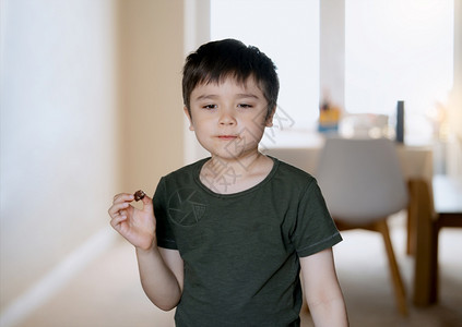 黑暗的肮脏男可爱孩吃巧克力蛋糕快乐的孩子在吃巧克力的时候看着外面肖像小子放松和在家吃点心或甜图片