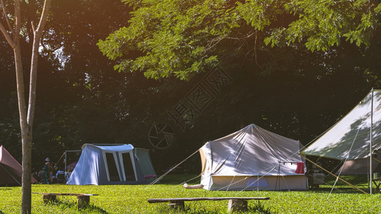 野外帐篷和旅行者团体在自然公园地带露营区绿草地的阴影下放松图片