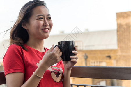 吸引人的积极女士Yip年轻的亚洲女饮咖啡杯在与城市背景交融的点上喝咖啡图片