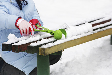 照片冬季游戏一个儿童坐在雪中一个旧长椅旁雕塑雪球的画面无聊灰色图片