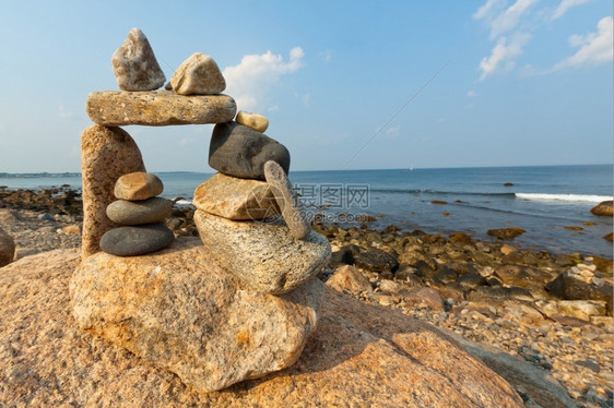 多岩石的海岸线罗得岛海滨的日落景通过象zen一样的石头结构云图片