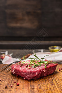 乡村新鲜的炖生牛肉排配有在黑织背景的生锈风衣桌上烹饪的原料图片