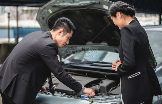 使固定扳手机械商人帮助女检查和修理破损的汽车图片