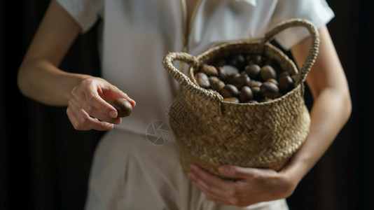 植物手持栗子的人里拿着栗子边上装满了栗子的铁球篮季节食物图片