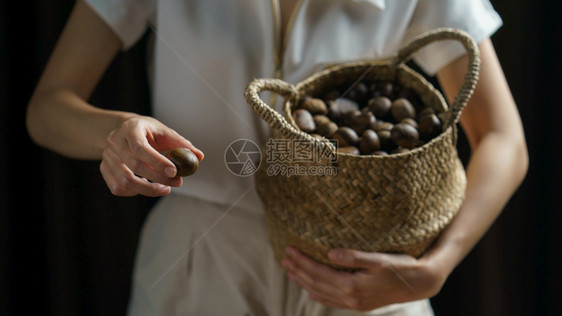 植物手持栗子的人里拿着栗子边上装满了栗子的铁球篮季节食物图片