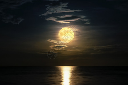 宁静午夜时分超满月和黄天空的云在海洋地平线上方月光反映水面和波浪夜晚海景风美丽的自然观以作为背夜间海视图浪漫的反射图片